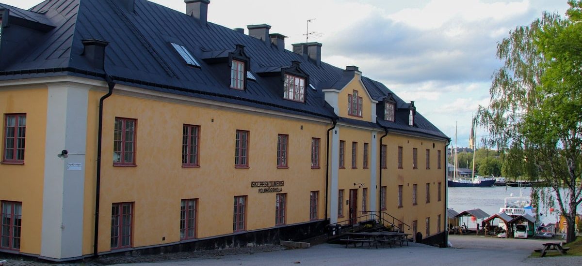 A yellow building faces the water on a cloudy day.